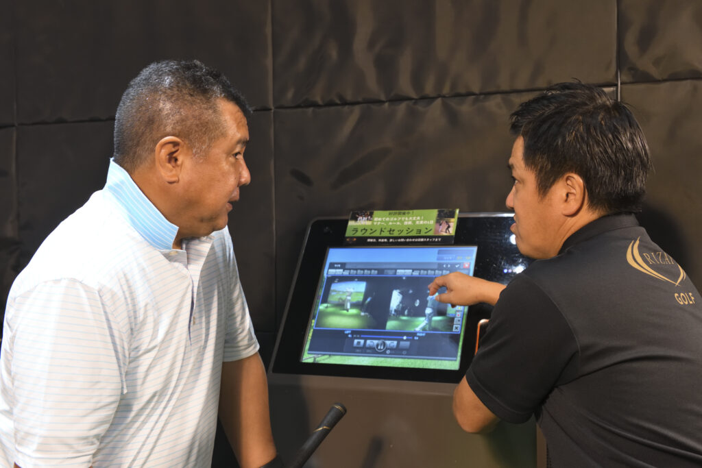 RIZAP GOLFでスイング映像とデータを確認する利用者とトレーナー